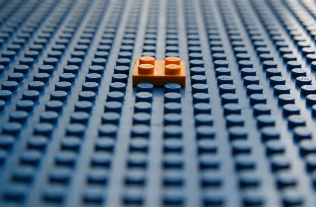 orange lego block in constrast in a floor of legos