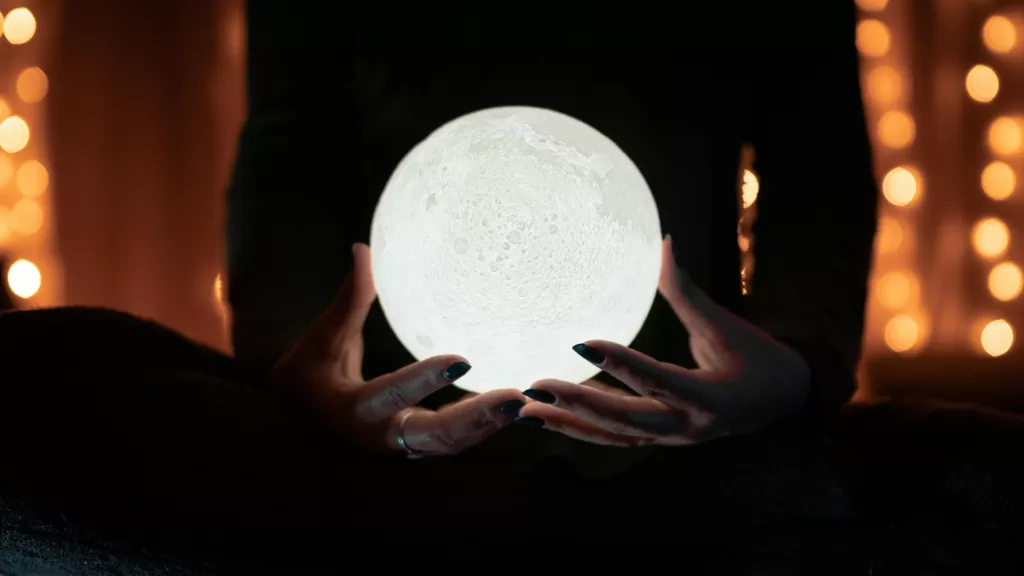 Someone holding a white round object that looks like the moon.